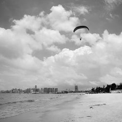 View of person paragliding over city against sky