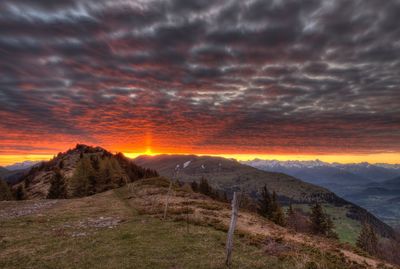 Scenic view of landscape against dramatic sky during sunset