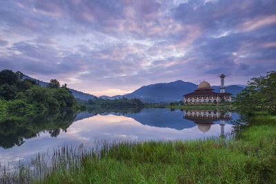 Scenic view of lake by building against sky during sunset