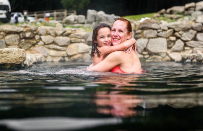 Portrait of happy mother and daughter embracing in lake