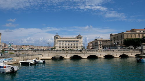 Bridge over river in city against sky