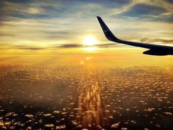 Silhouette airplane flying over landscape against sunset sky