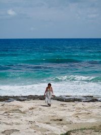 Full length of woman walking at beach against sea and sky