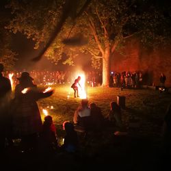 Crowd looking at performer performing with fire at night