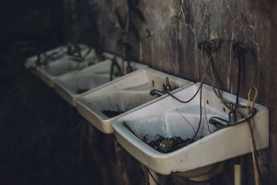 Close-up of abandoned sinks against wall