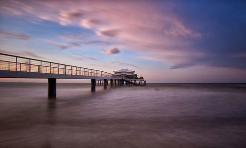 Pier over sea against sky at sunset