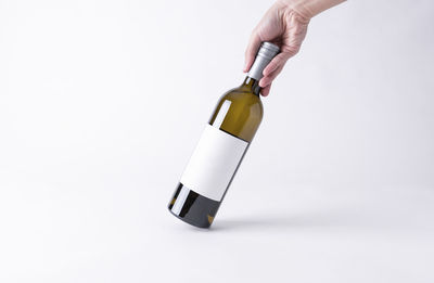 Close-up of hand holding bottle against white background