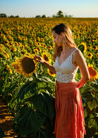 Young woman standing amidst plants on field