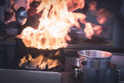 Midsection of chef cooking food in flames
