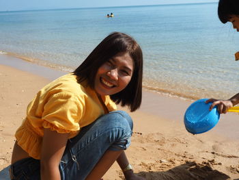 Portrait of happy woman sitting on beach