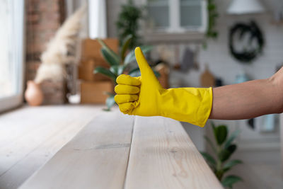 Cropped image of hand holding yellow leaf on wood