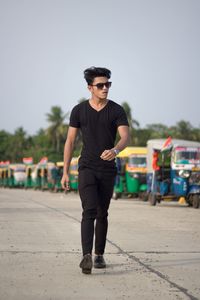 Portrait of young man standing on road against clear sky