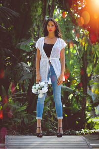 Portrait of young woman standing against plants