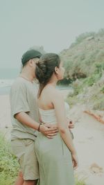 Side view of couple standing at beach