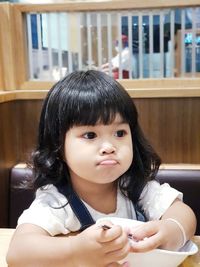 Cute girl looking away sitting at table in restaurant