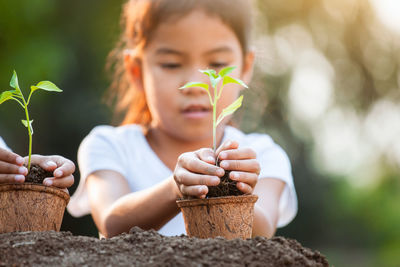 Close-up of girl holding plant in hand outdoors