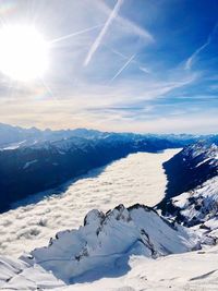 Scenic view of snowcapped mountains against bright sun