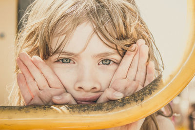 Close-up portrait of cute girl looking through railing