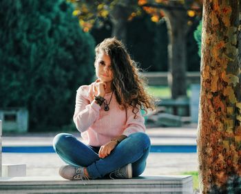 Portrait of young woman sitting on tree