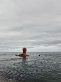 Rear view of man in sea against sky
