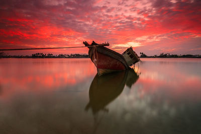 Boat in lake against sky during sunset