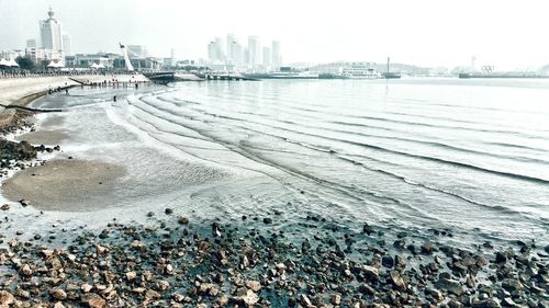 Sea and beach in city against sky