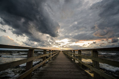 Pier over sea against sky during sunset