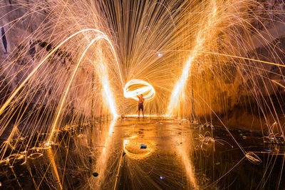 Man spinning wire wool while standing on land at night