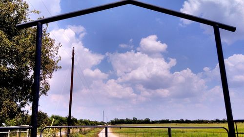 Trees on field against cloudy sky