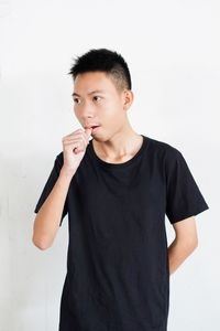 Close-up of young man standing against white background