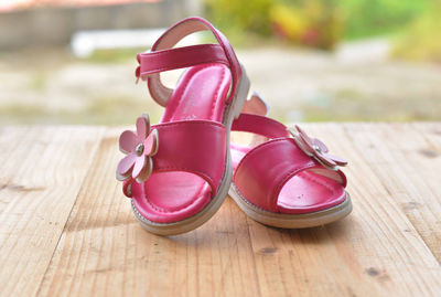 Close-up of pink sandals on wooden table