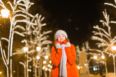 Portrait of woman standing on illuminated during winter at night