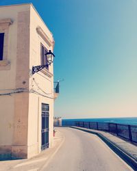 Road by building against clear blue sky