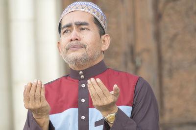 Close-up of mature man praying while sitting at mosque
