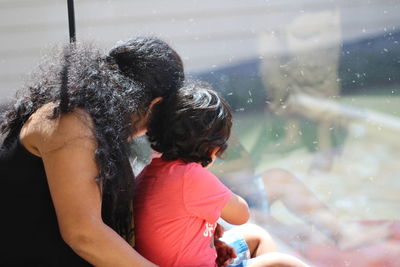 Side view of woman with his son looking out through glass window
