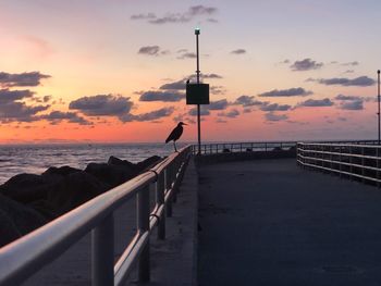 Silhouette man on pier by sea against sky during sunset