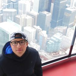 Portrait of young man standing against buildings in city