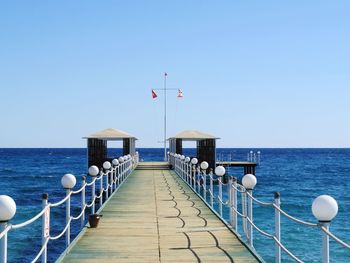 Pier over sea against clear blue sky
