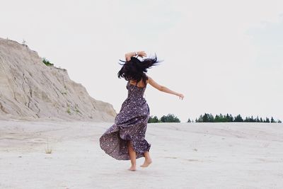 Full length of happy young woman spinning on land