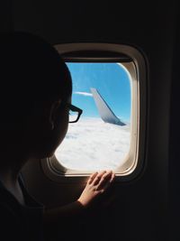 Close-up of woman looking through window while traveling in airplane