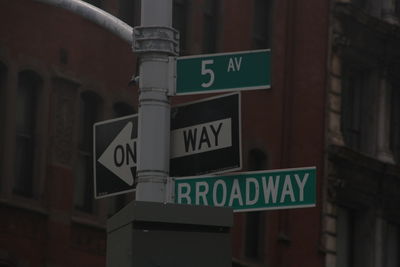 Low angle view of road sign against built structure