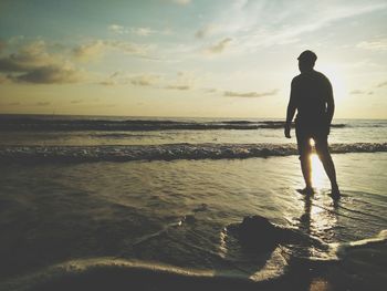 Silhouette man standing at beach against sky