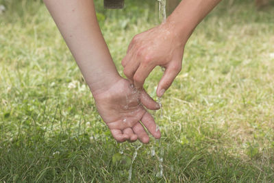 Cropped hand of person cleaning hands with water outdoors