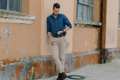 Full length of young man standing against building