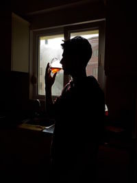 Side view of a man drinking glass at home