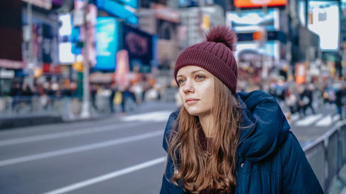 Portrait of young woman standing on street in city