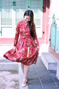 Full length of smiling young woman in floral dress walking outdoors