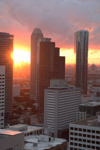 Modern buildings in city against sky during sunset