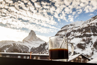 Close-up of tea cup against snowcapped mountains