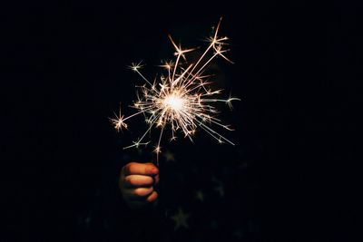 Person hand holding sparkler at night
